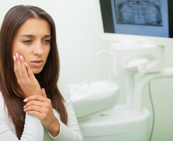 Young female having toothache. Upset woman at the dentist. Constant pulsating pain