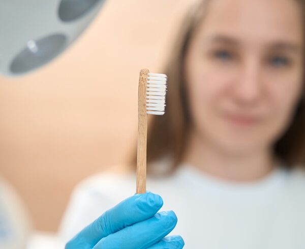 Woman dentist in dental office holds toothbrush in her hands